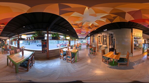 Een restaurant met een modern interieur, met houten tafels en stoelen, een visgraatvloer en een plafond met geometrische patronen.
