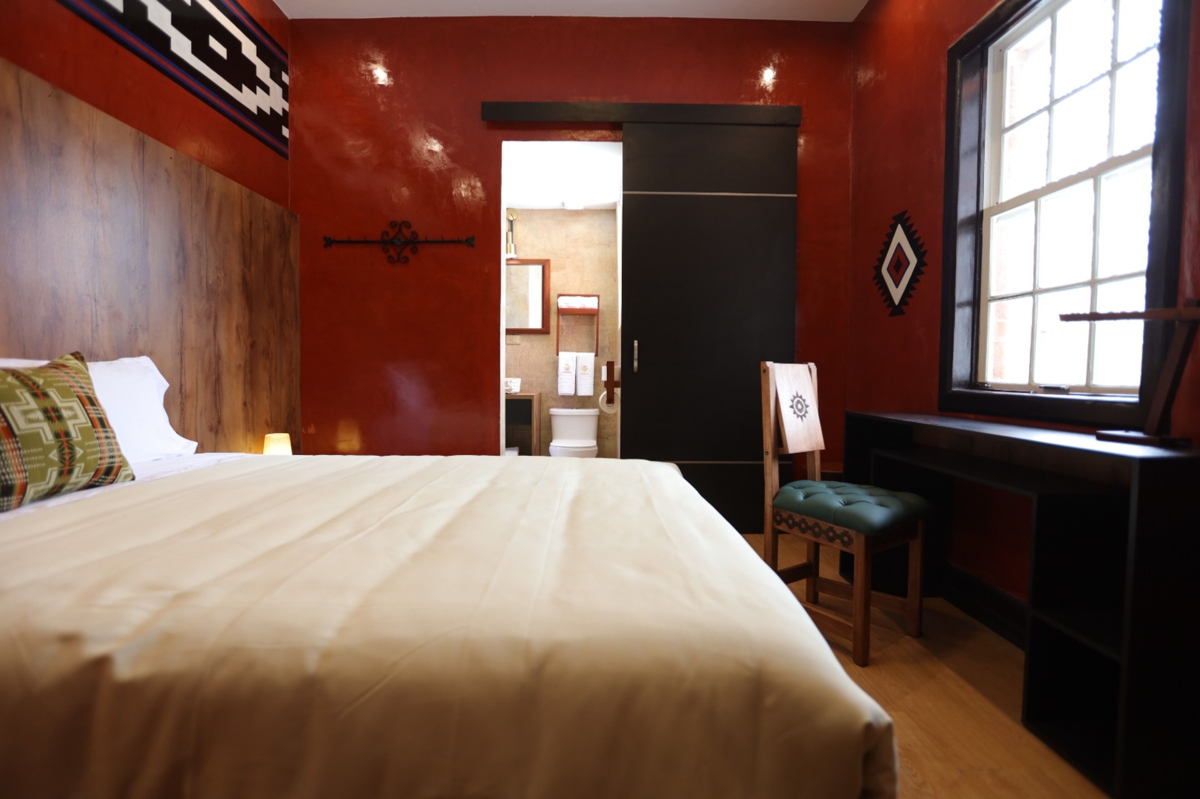 Habitación de hotel con una cama grande, un escritorio, una silla y un ventanal.