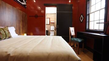 Habitación de hotel con una cama grande, un escritorio, una silla y un ventanal.