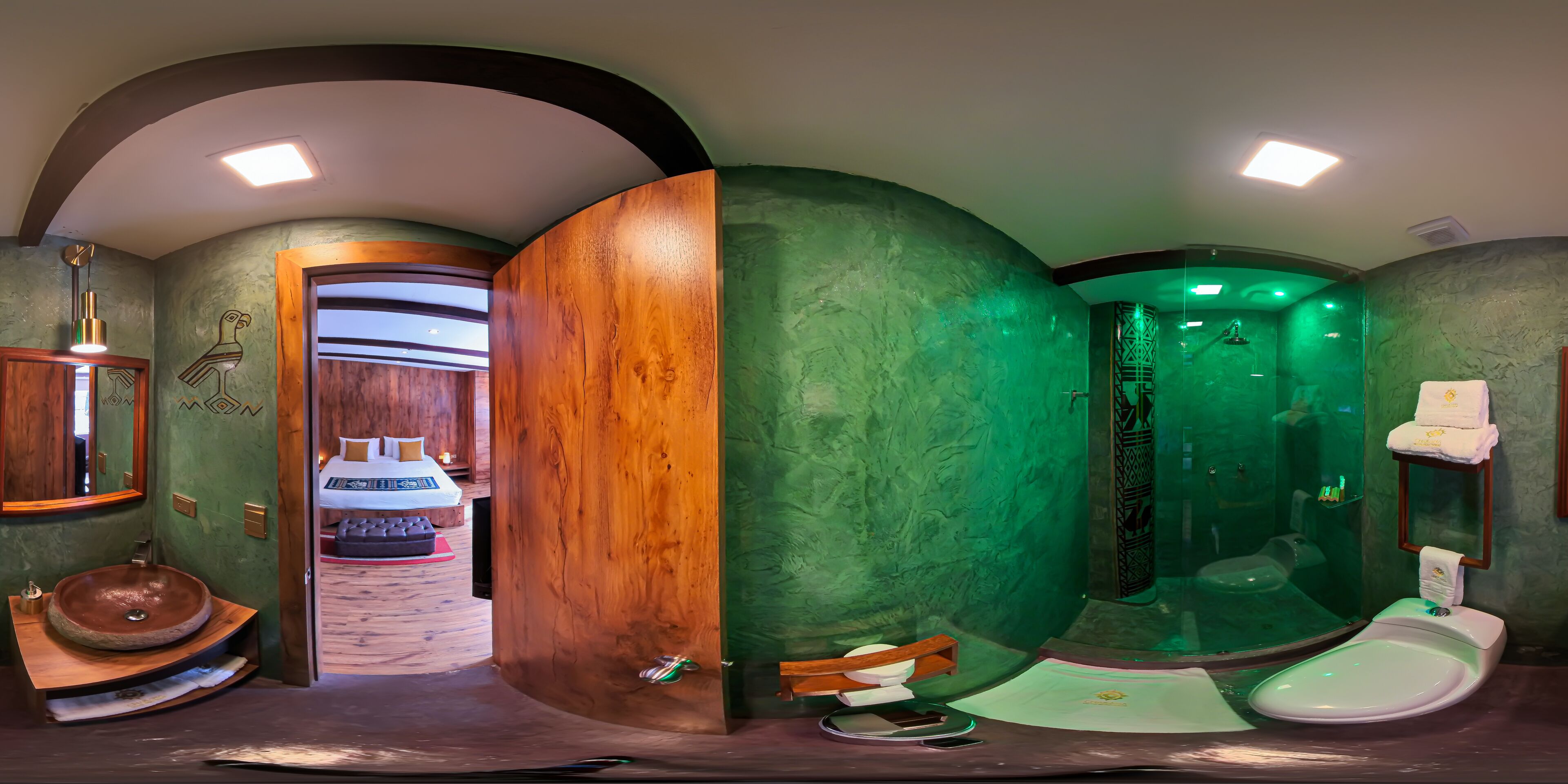 A bathroom with a wooden vanity, a round sink, and a green-tiled shower area.