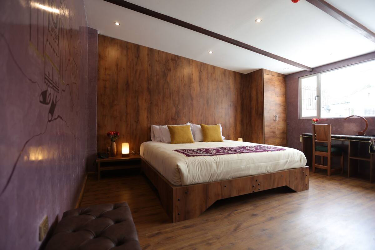 Une chambre à coucher avec un lit en bois, une table de chevet avec une lampe et un bureau avec une chaise.