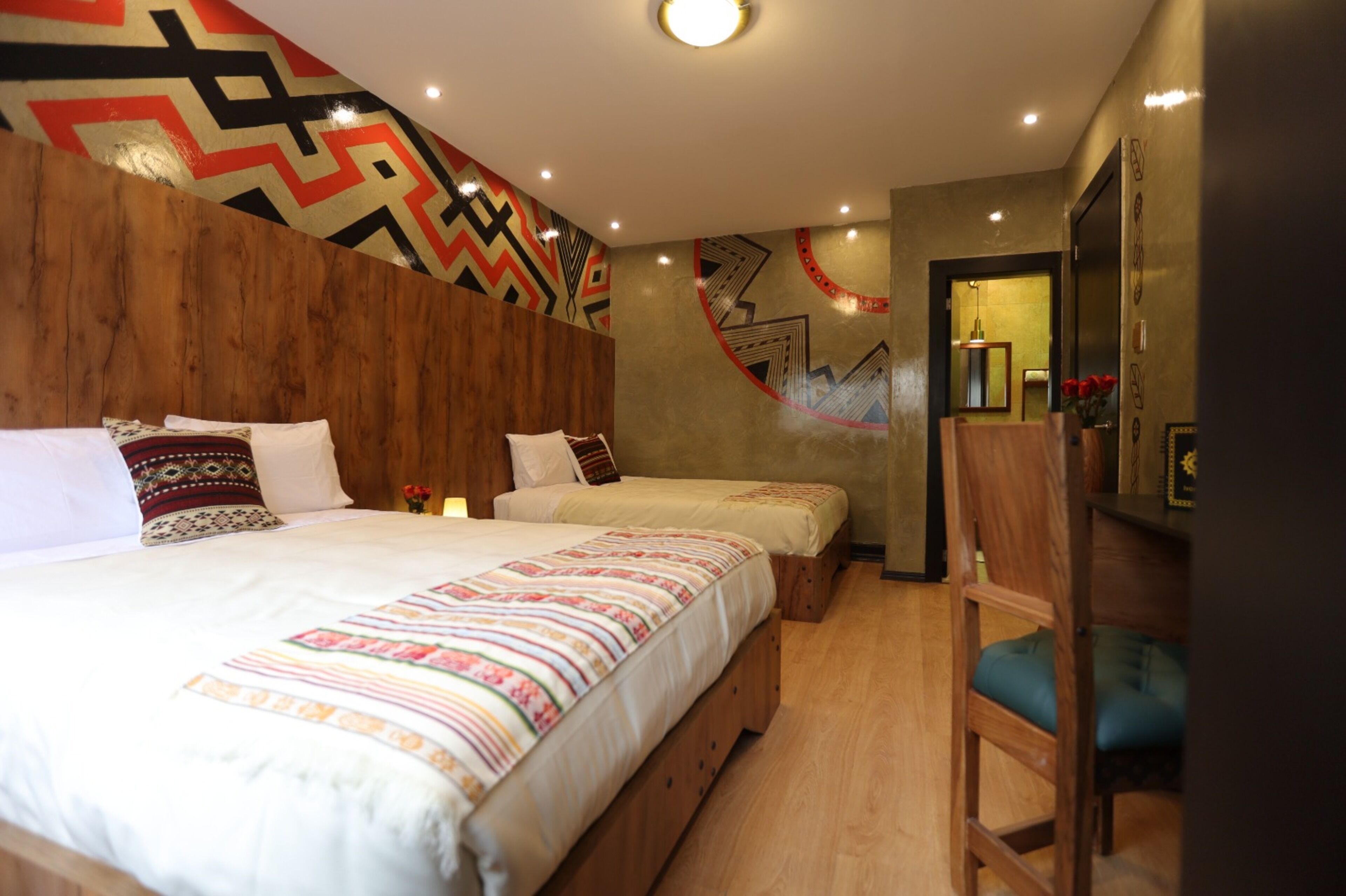Una habitación de hotel con dos camas, cabeceros de madera y un mural grande en la pared.
