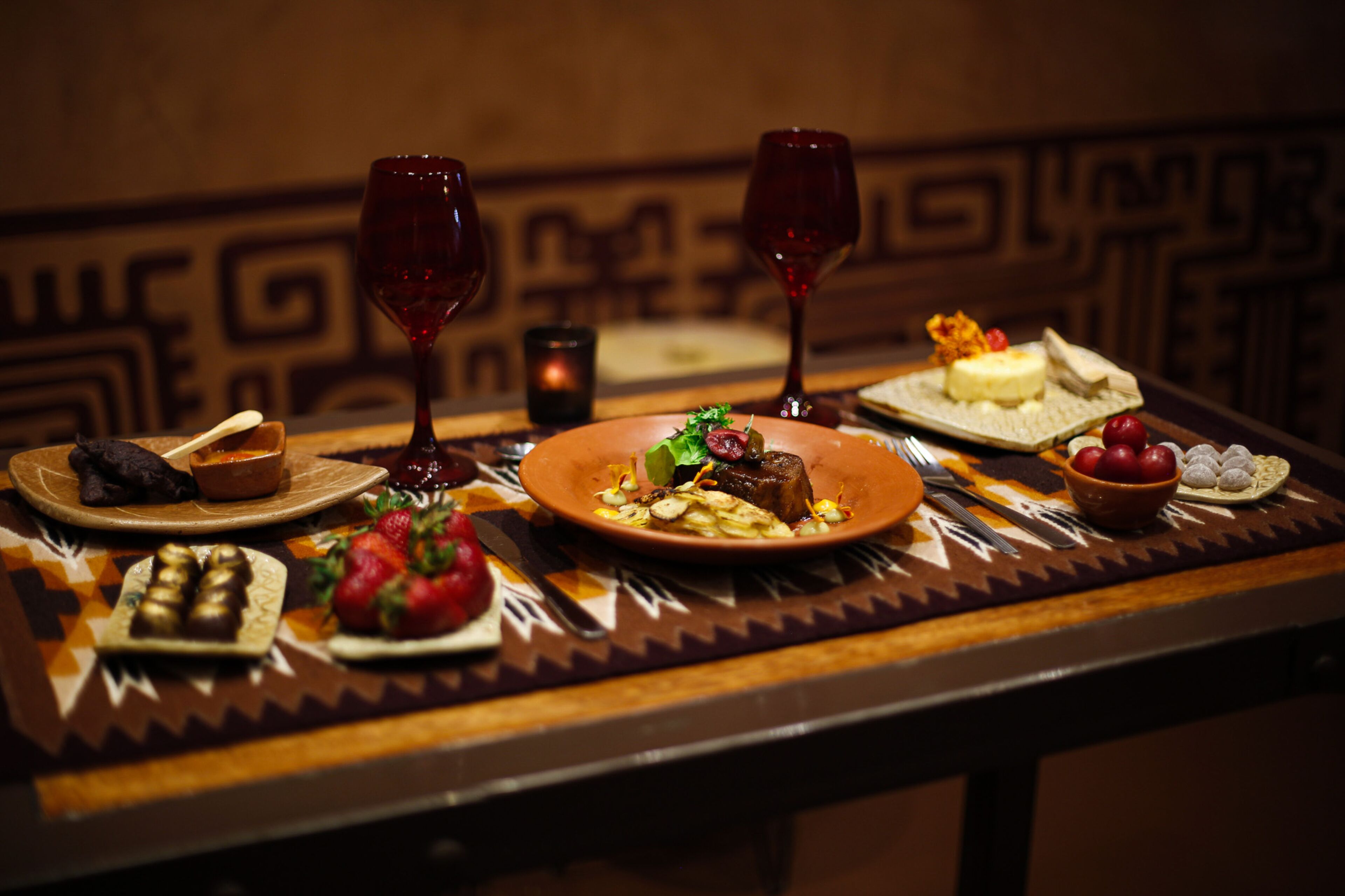 A dining table with various dishes, wine glasses, and cutlery.