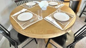 Ett runt matbord dukat för fyra personer, med vita tallrikar, glas och servetter.