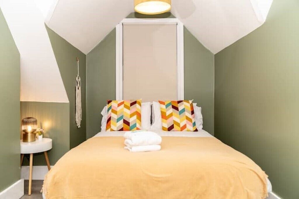 A bedroom with a bed, pillows, a bedside table, and a lamp.