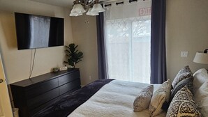 A bedroom with a bed, a dresser, a TV mounted on the wall, and a window with curtains. - Vista Rental 1 Cozy Home, 25 min from Zion National Park (La Verkin)