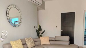 Ein modernes Wohnzimmer mit einem Ecksofa, einem Glastisch und einem großen Spiegel.