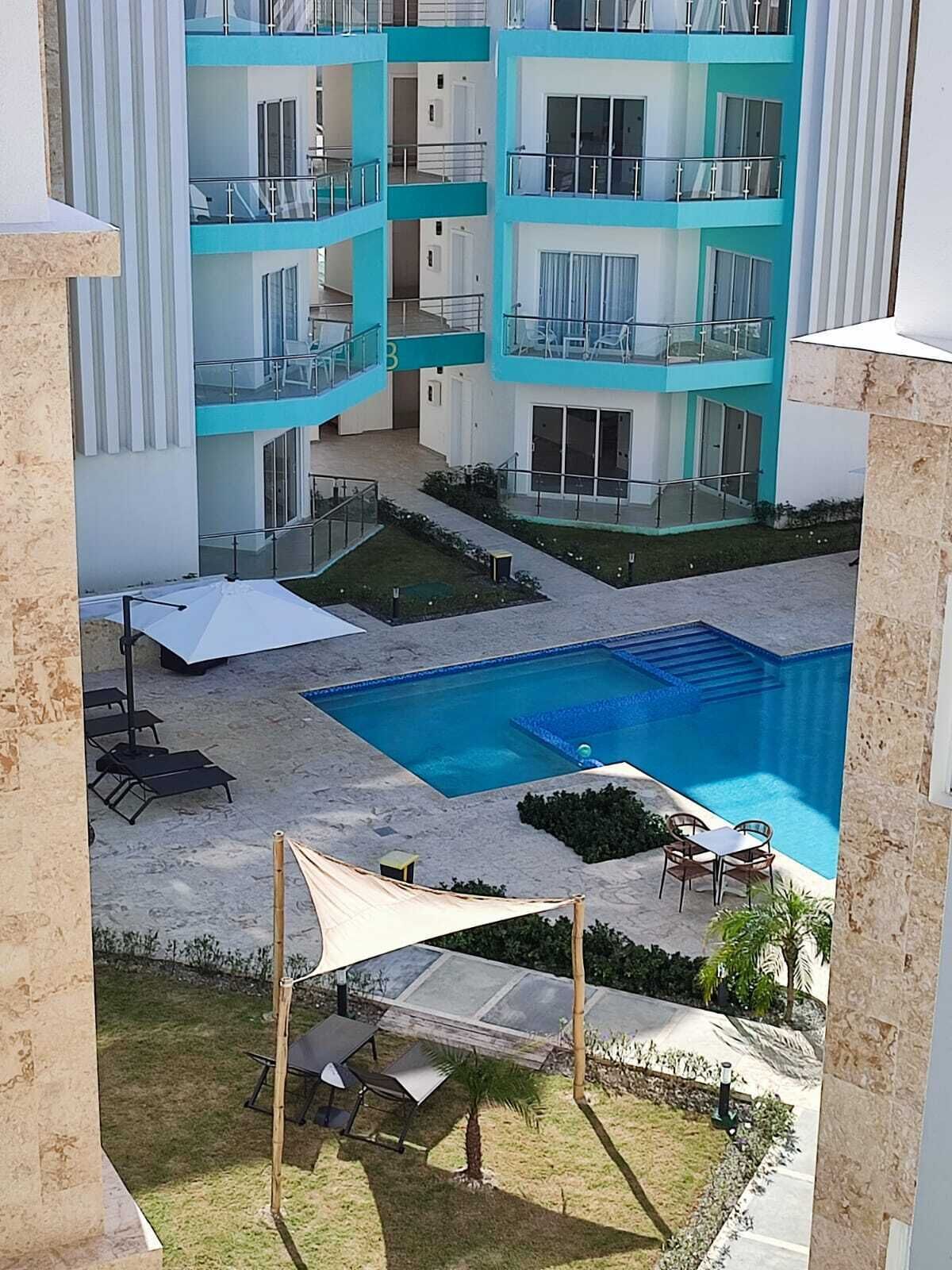 A multi-story building with balconies, a swimming pool, and outdoor seating areas.