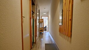 A narrow hallway with wooden paneling on the walls, a wooden floor, and a door at the end. - 10m from ski slopes, 1st floor, balcony, tv, 34m², Chamrousse (Chamrousse)