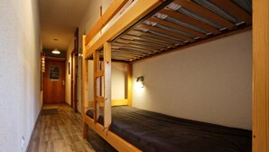 A narrow hallway with a bunk bed on the right, wooden flooring, and a door at the end. - 10m from ski slopes, 1st floor, balcony, tv, 34m², Chamrousse (Chamrousse)