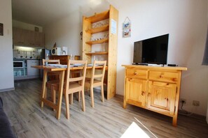 A compact living space with a dining area, a kitchenette, and a TV on a wooden cabinet.