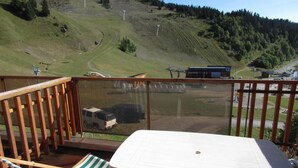 A balcony with a table and chairs overlooking a mountainous area with ski lifts. - 10m from ski slopes, 1st floor, balcony, tv, 34m², Chamrousse (Chamrousse)