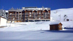 A multi-story lodge with a symmetrical facade, large windows, and a snow-covered roof. - 10m from ski slopes, 1st floor, balcony, tv, 34m², Chamrousse (Chamrousse)