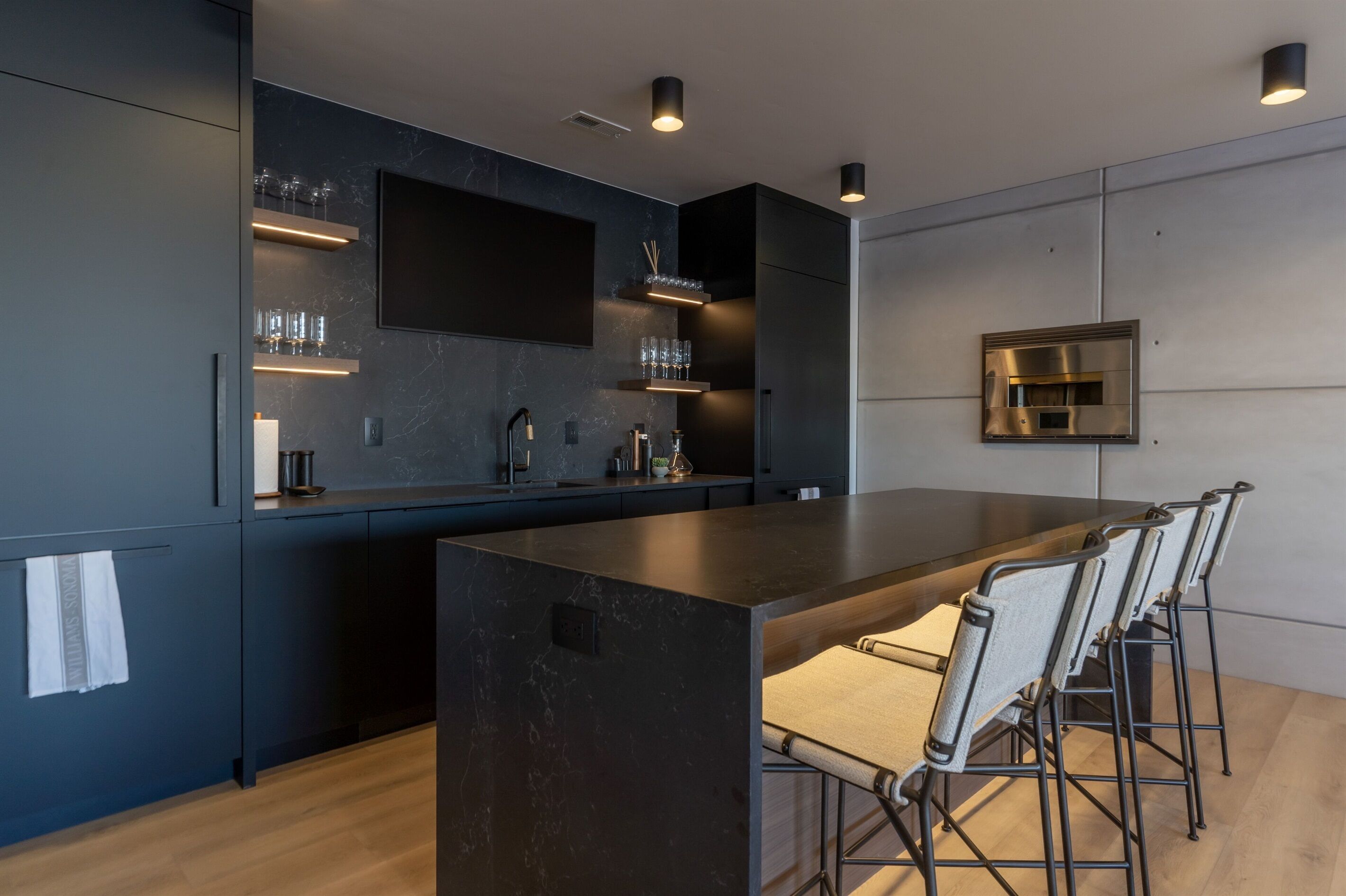 A modern kitchen with a large island, built-in appliances, and a dining area with bar stools.