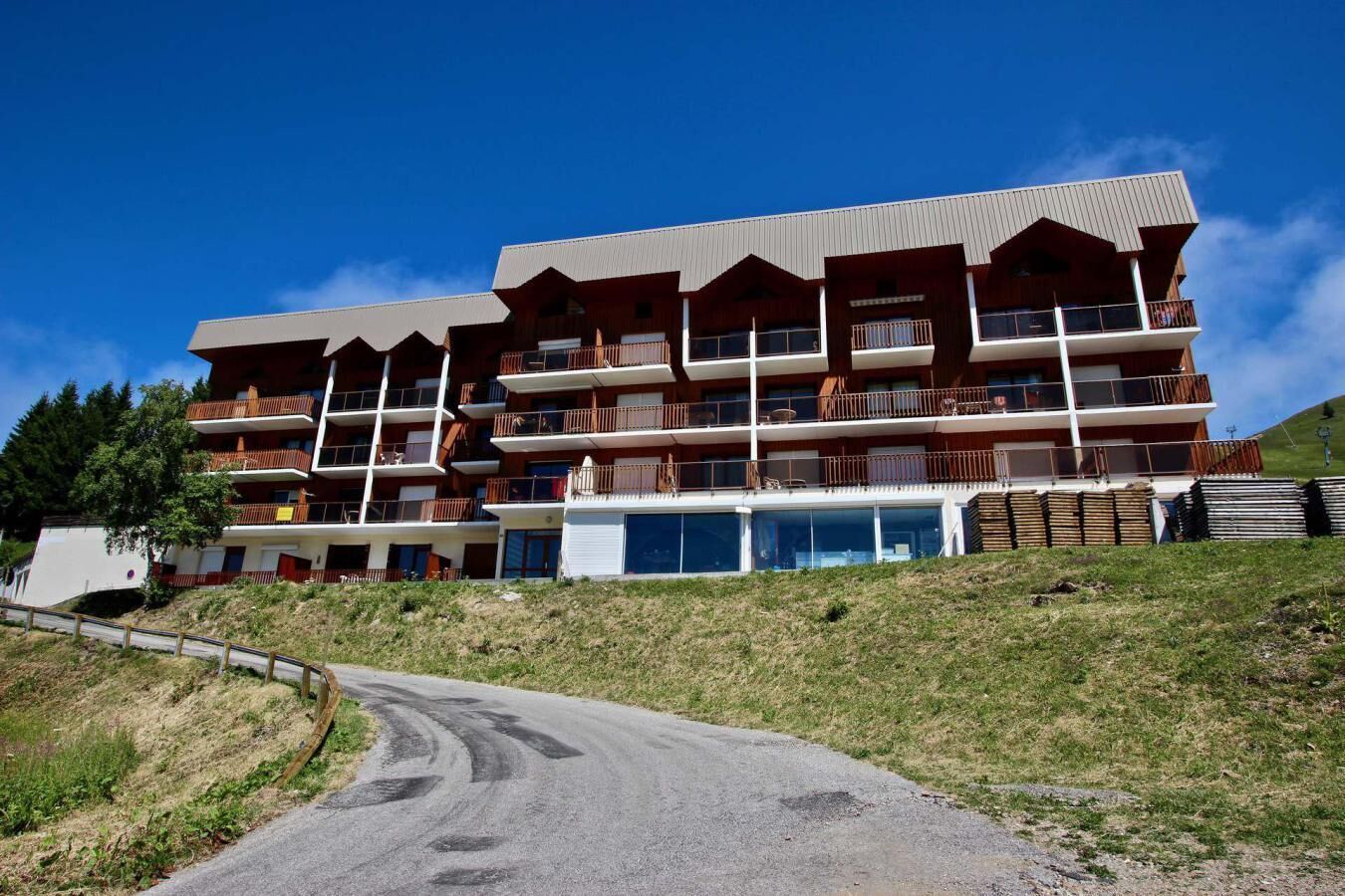 Un hôtel à plusieurs étages doté de balcons, d’une piscine et situé dans un paysage vallonné.