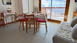 A dining area with a table set for four, chairs with cushions, a wooden bench, and a sofa. - 10m from ski slopes, 1st floor, balcony, tv, 22m², Chamrousse (Chamrousse)