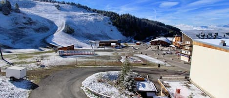 A snow-covered parking area with buildings and a road curving through it.