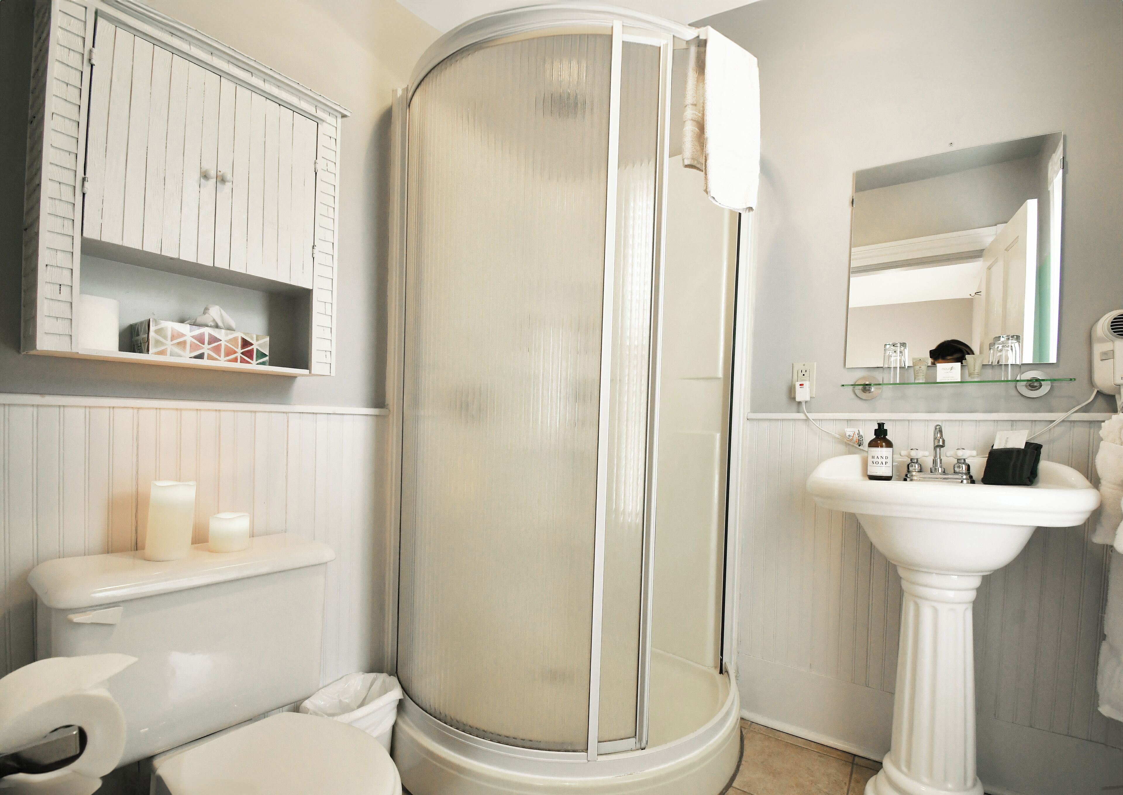 A bathroom with a toilet, a sink, a shower with a glass door, and a mirror.