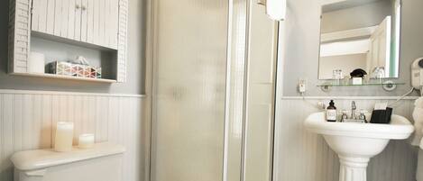 A bathroom with a toilet, a sink, a shower with a glass door, and a mirror.