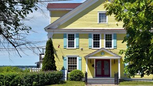 A two-story yellow building with a red door and blue shutters, surrounded by greenery. - Hotel Gabriel by Bower Boutique Hotels (Shediac)