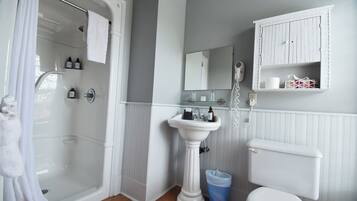Un baño con ducha, lavamanos pedestal, inodoro y espejo.