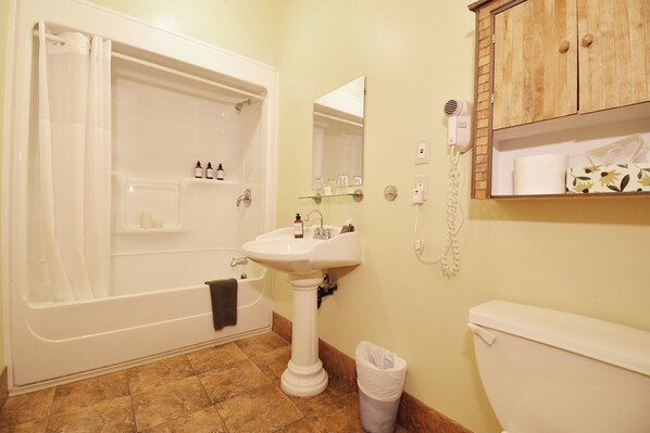 A bathroom with a bathtub, sink, mirror, and toilet.