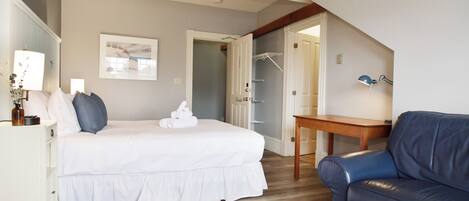Un dormitorio con cama, mesita de noche, lámpara y sofá azul.