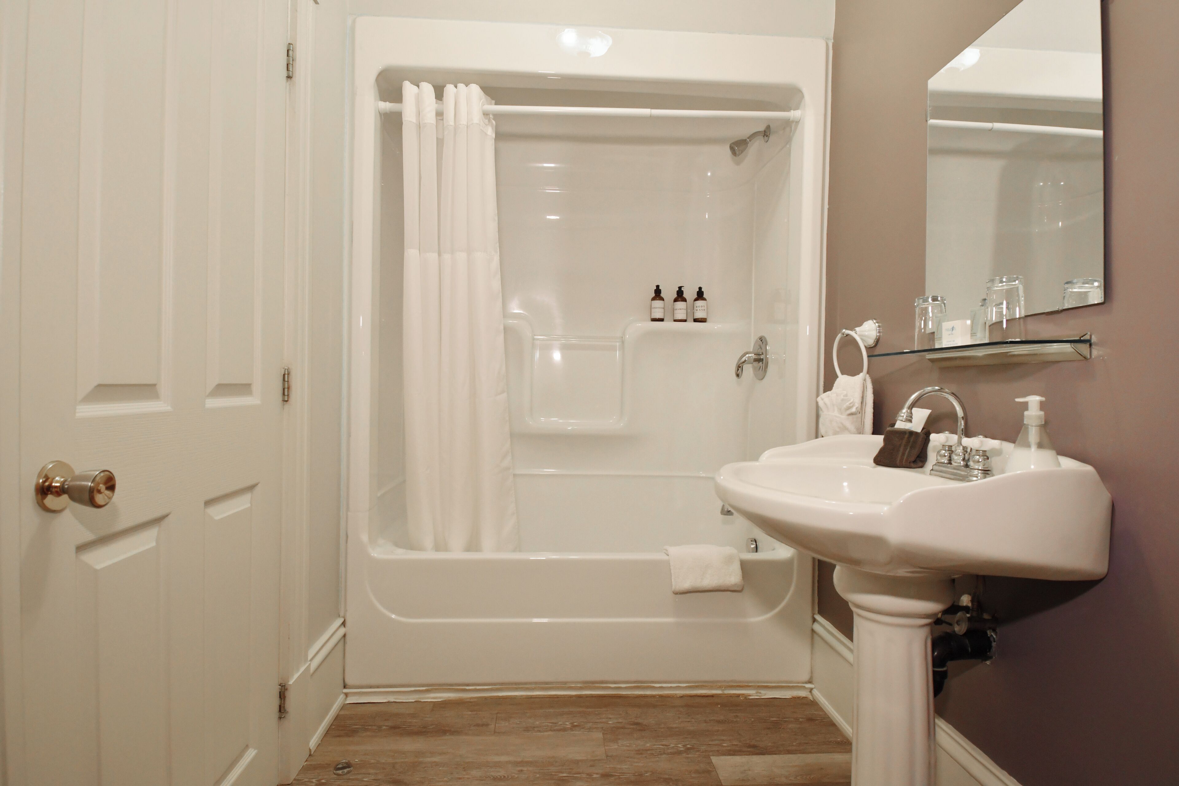 A bathroom with a bathtub, a sink, and a mirror.