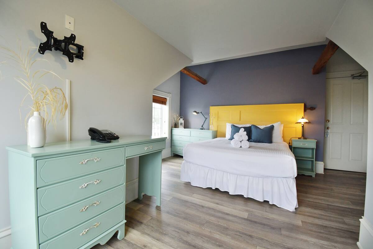 A bedroom with a bed, a desk, a dresser, and a nightstand.