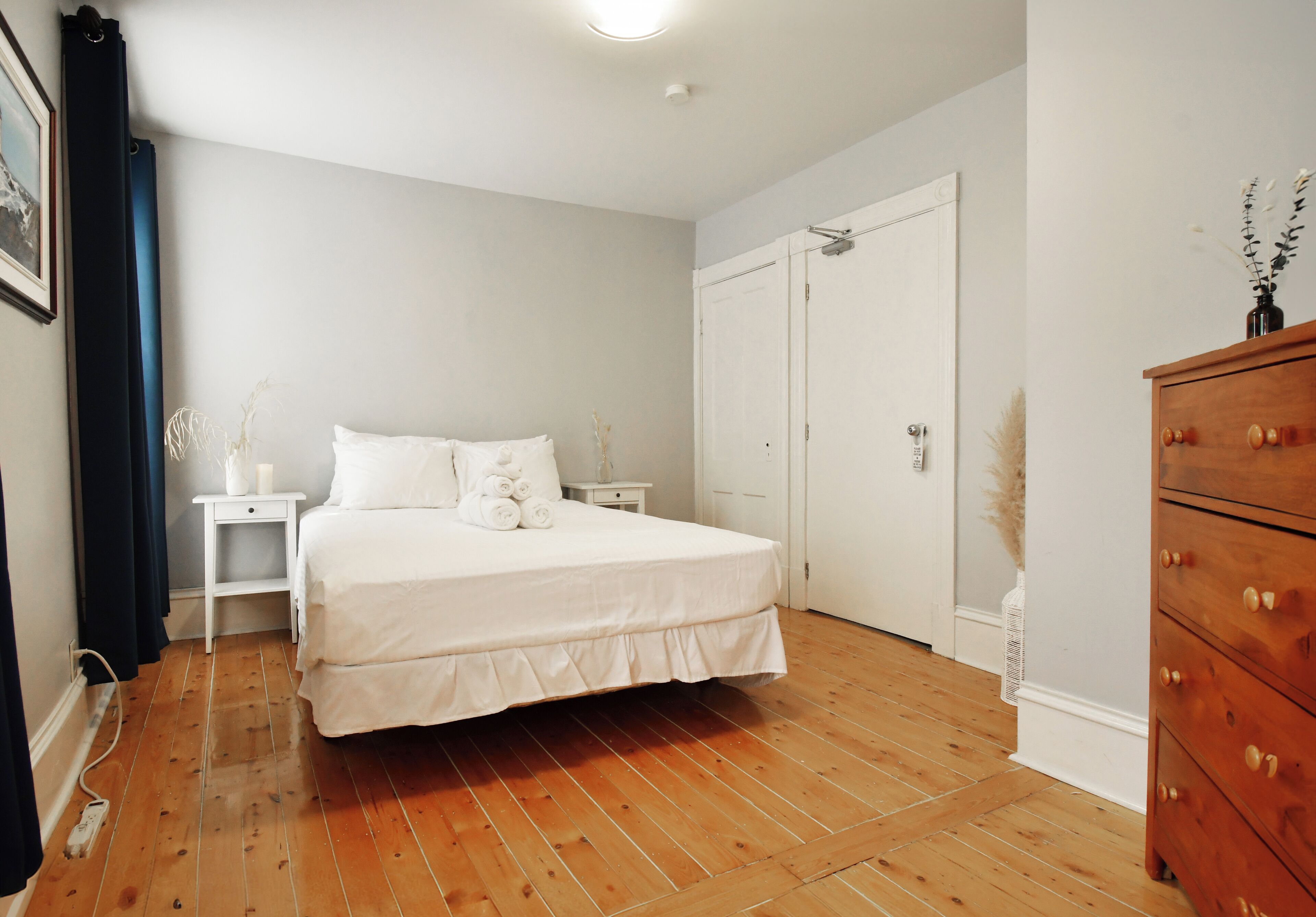 A bedroom with a bed, a nightstand, a dresser, and a wardrobe.