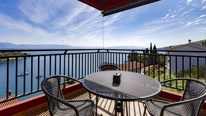 A balcony with a table and chairs overlooking a lake with boats, surrounded by greenery and mountains. - Apartment mit Wunderschönem Meerblick nur 5 Minuten vom Strand Entfernt (Sveta Marina)