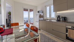 A modern kitchen with a glass dining table, orange chairs, and a view to the outside. - Apartment mit Wunderschönem Meerblick nur 5 Minuten vom Strand Entfernt (Sveta Marina)