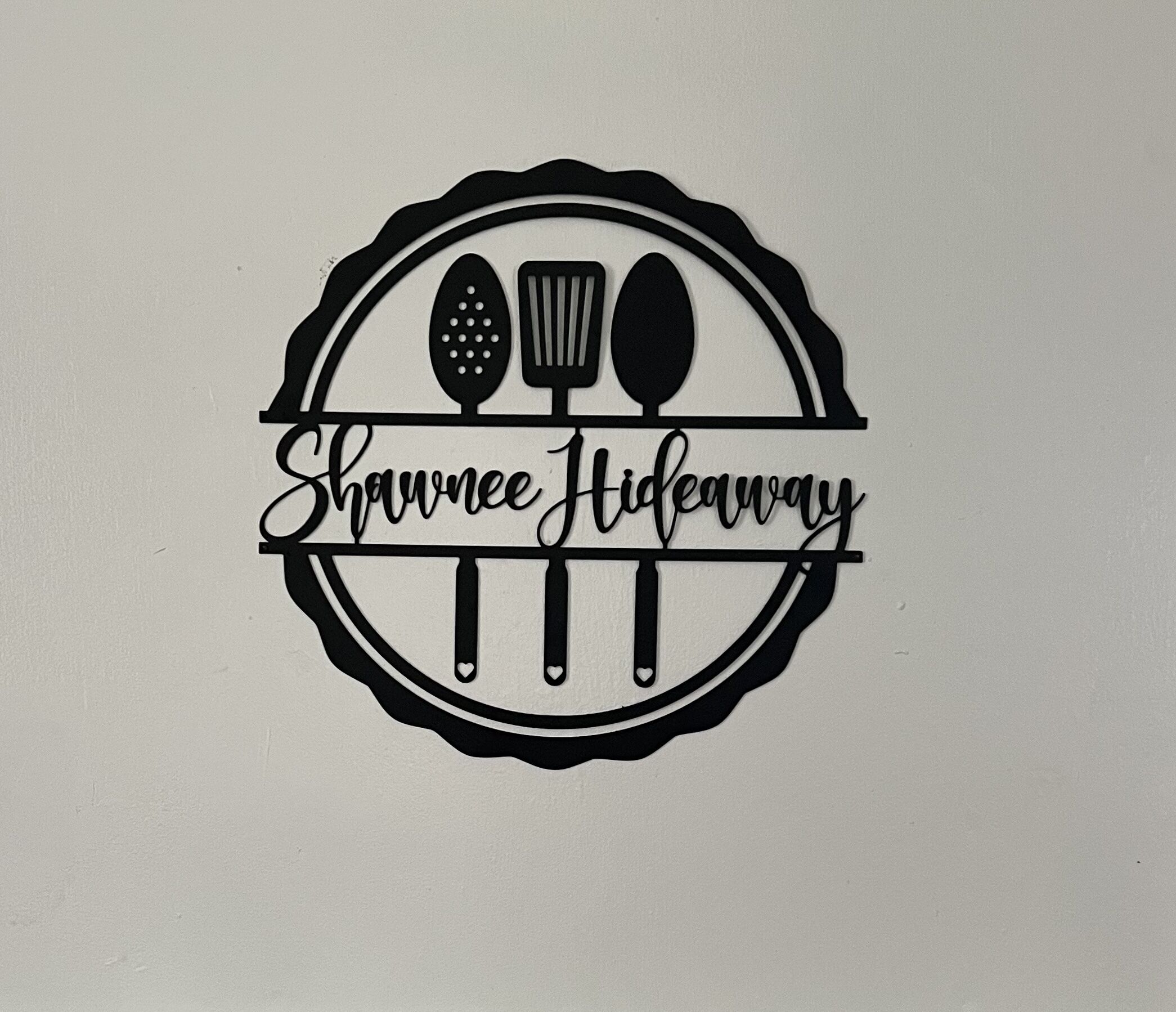 Ein Logo mit Küchenutensilien und dem Text 'Shawnee Hideaway'.