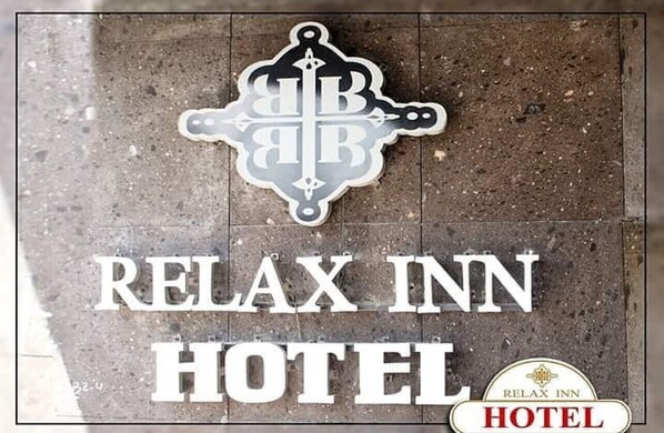A sign for the Relax Inn Hotel with a decorative emblem above the text.