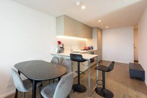A compact kitchen with a dining area, including a table and chairs, and a small bar stool.