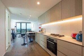 A modern kitchen with a gas stove, oven, and bar stools.