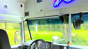 Interior de autobús con volante, tablero de control y una figurita sobre el tablero.