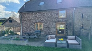 Un bâtiment en pierre doté d’un patio aménagé avec des sièges et une table pour l’extérieur.