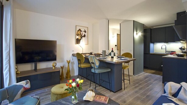 A modern living room with a flat-screen TV, a dining area with a bar, and a kitchen with dark cabinetry. - 50m from resort center, Ground floor, tv, ski locker, 50m², Les 2 Alpes (Mont-de-Lans)