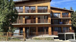 A multi-story wooden building with balconies, a parking lot, and a sign indicating availability for rent. - 300m from ski slopes, 2nd floor, balcony, tv, ski locker, 48m², Les 2 Alpes (Mont-de-Lans)