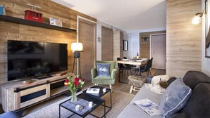 A modern living room with a TV, sofa, coffee table, and a dining area with chairs and a table. - 300m from ski slopes, 2nd floor, balcony, tv, ski locker, 48m², Les 2 Alpes (Mont-de-Lans)