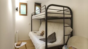 Ein Schlafraum mit Etagenbetten, einem kleinen Tisch, einem Stuhl, einem Teddybären und einem Fenster.