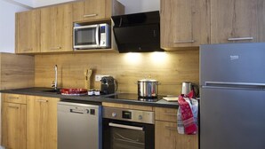 Eine moderne Küche mit Holzausstattung, einem Edelstahlkühlschrank, einer Mikrowelle, einer Kaffeemaschine und einem Geschirrspüler.
