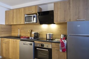 A modern kitchen with wooden cabinets, a stainless steel refrigerator, a microwave, a coffee maker, and a dishwasher. - 50m from resort center, 2nd floor, balcony, tv, ski locker, 48m², Les 2 Alpes (Mont-de-Lans)