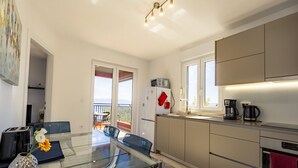 A modern kitchen with a glass dining table, a refrigerator, and a coffee maker. - Apartment mit Wunderschönem Meerblick nur 5 Minuten vom Strand Entfernt (Sveta Marina)