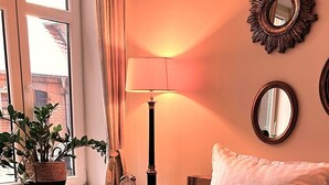 A hotel room with a bed, bedside lamp, bedside table, potted plant, and a magazine on the bed. - Lieblings-ort Lulu - Raum für Zeit (Ludwigslust)