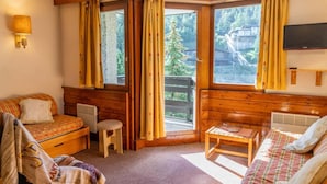 Una habitación acogedora de estilo cabaña con interior de madera, un sofá, una mesita y una ventana con cortinas.