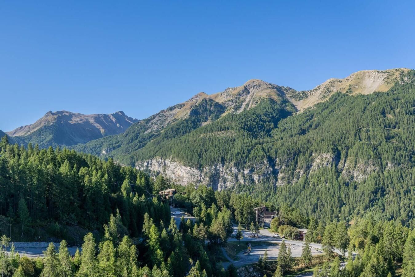 Un paysage montagneux, avec de vastes forêts et un ciel dégagé.