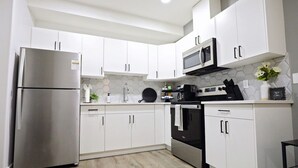 Een moderne keuken met witte kasten, roestvrijstalen apparatuur en een backsplash van hexagontegels.