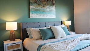 Een slaapkamer met een bed, twee bedlampen, een nachtkastje en een schilderij aan de muur.